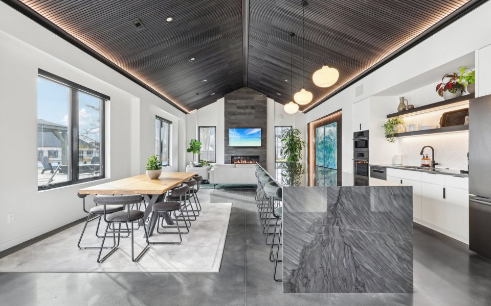 Long View of the Clubhouse Interior showing table seating, kitchen bar, couch and fireplace