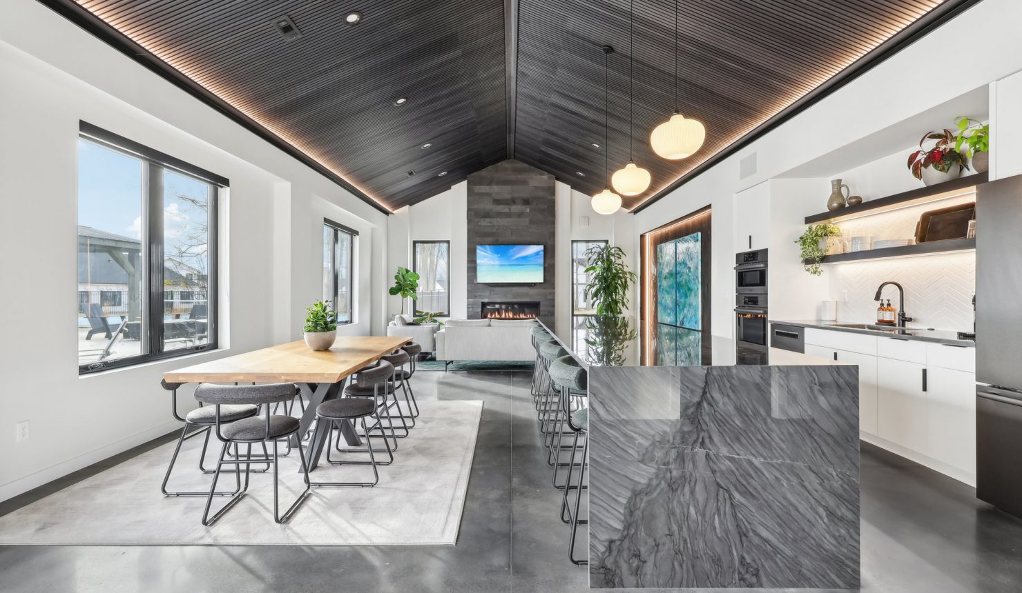 Long View of the Clubhouse Interior showing table seating, kitchen bar, couch and fireplace