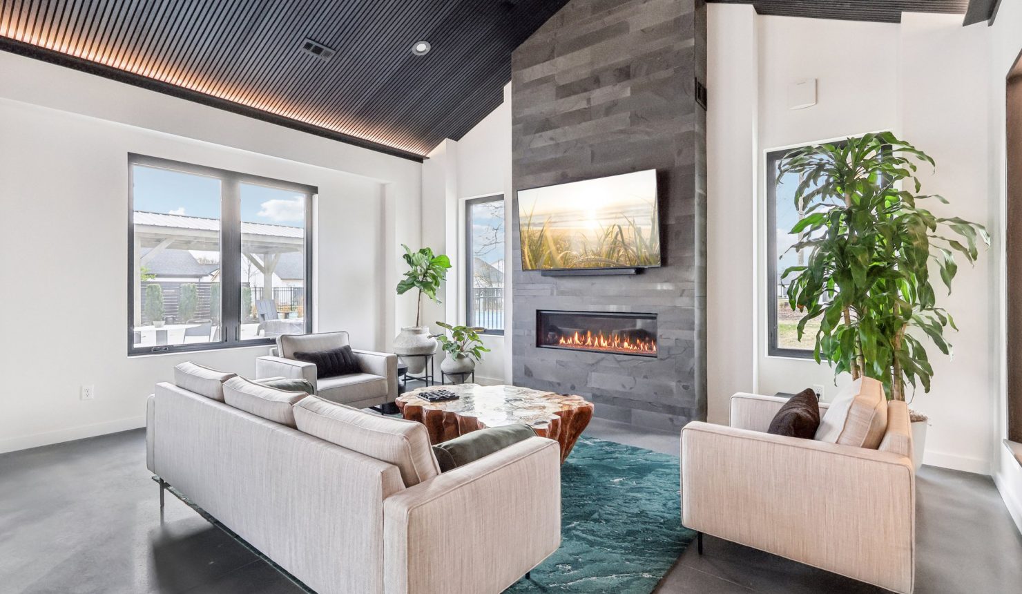 Lounge area in Club House with couch, chairs, fireplace and TV